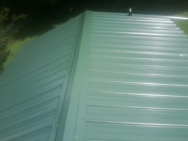 New green metal panels meeting at the ridge of a roof — Flat Roof Repair work by our crew in Tekoa
