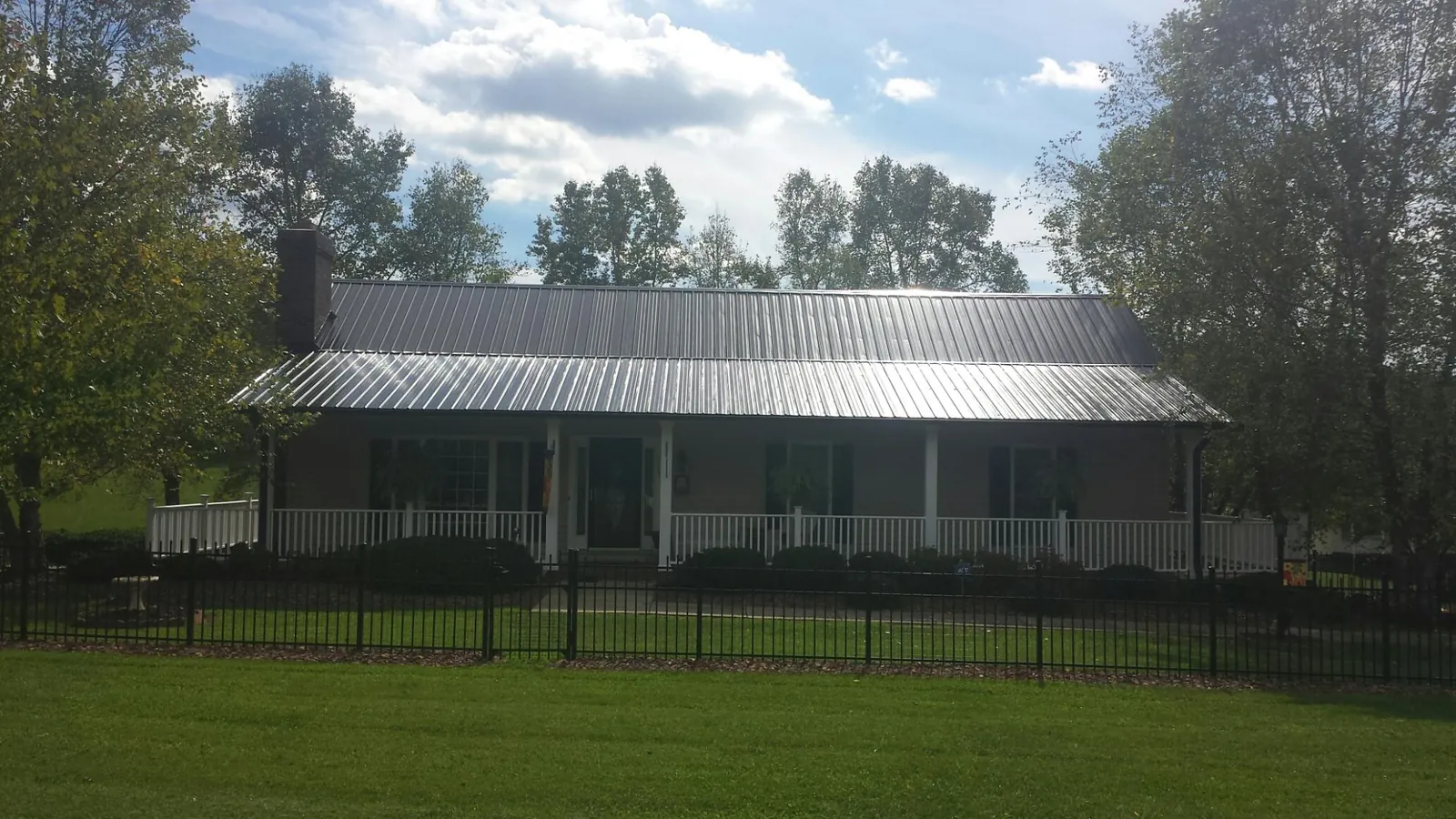Gray metal roof on a brick ranch with a full width front porch — Gutter Guard Installation work by our crew in Tekoa