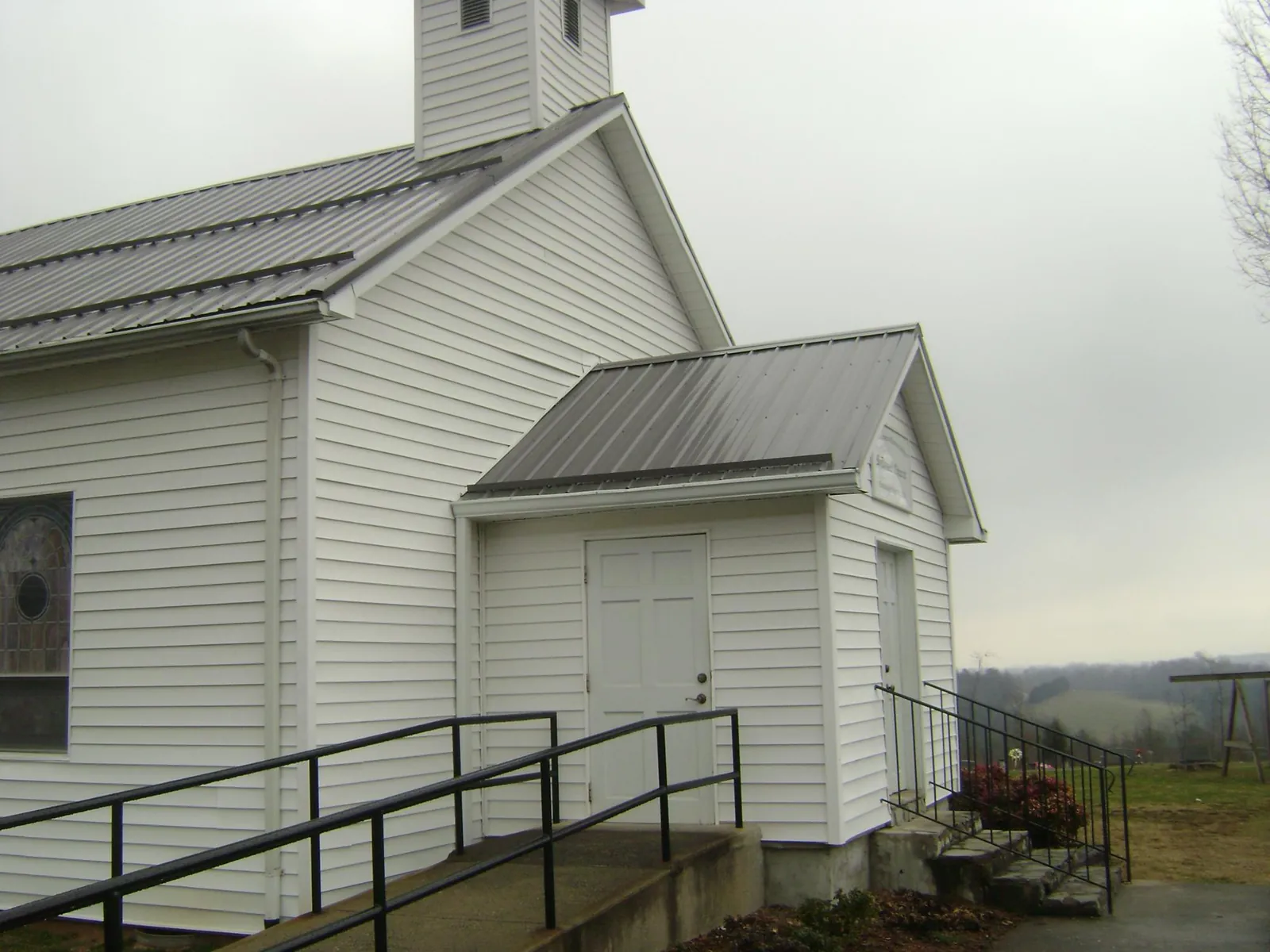 Gray metal roof on a white clapboard church with a steeple in Tekoa