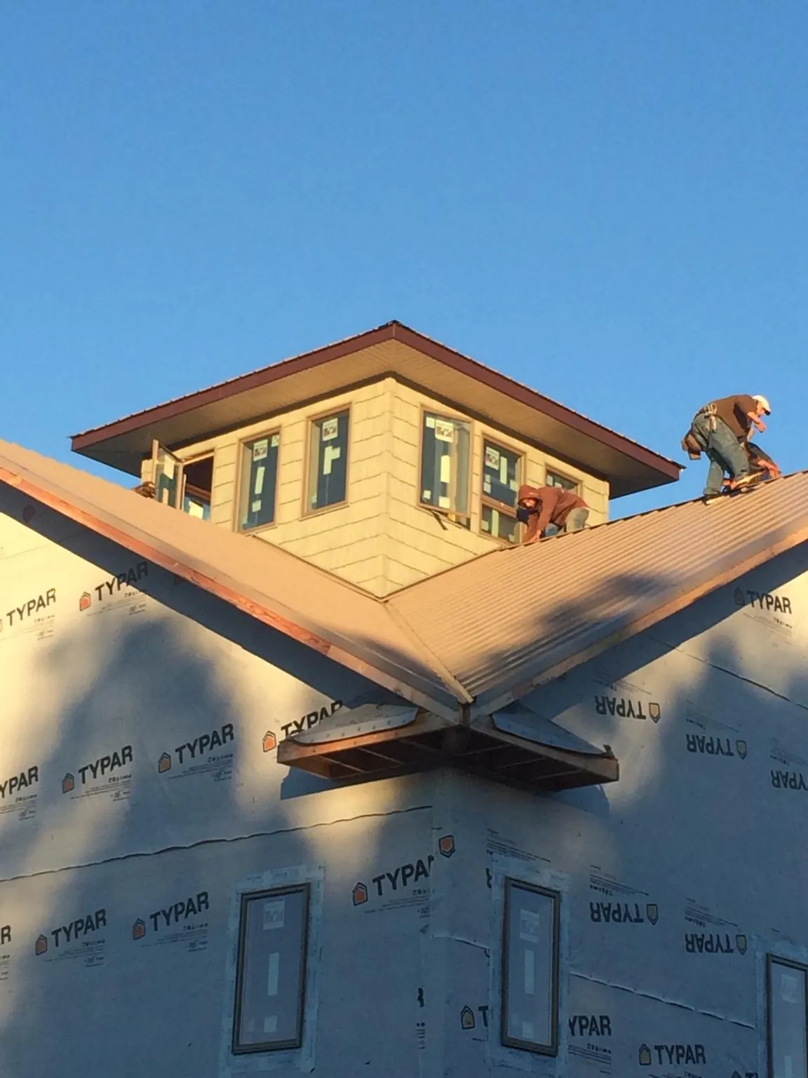 Roofers working around a rooftop cupola on a new metal roof at sunset — Roof Waterproofing in Tekoa by Roofing Brothers